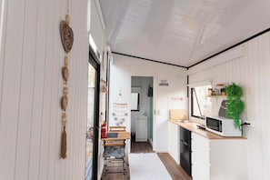 A narrow hallway with a bench, a microwave, and a small kitchen area.