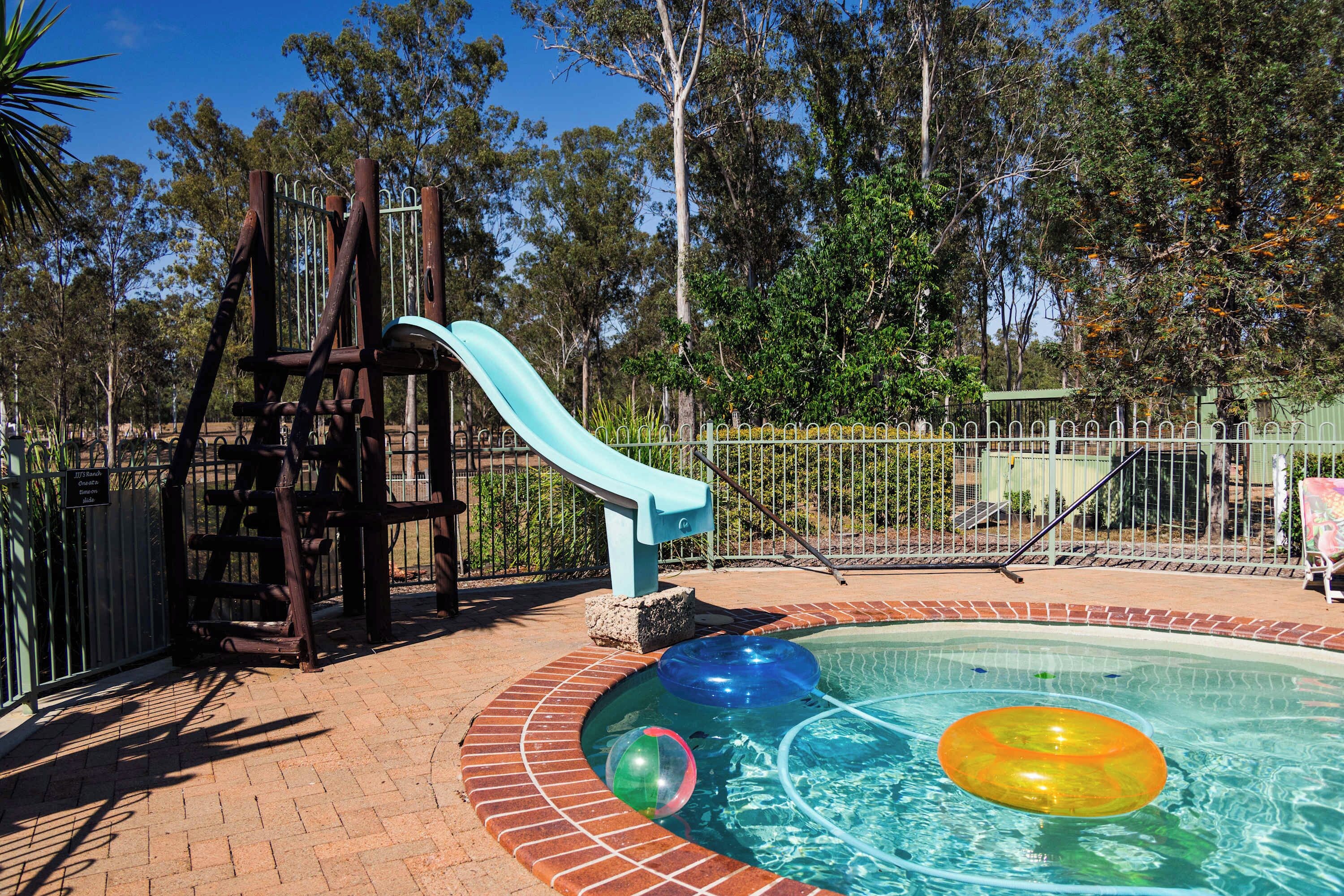 A playground with a slide and a pool with inflatable rings.