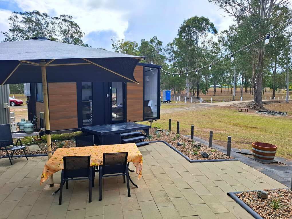 Un espace extérieur aménagé avec une structure couverte, des tables et des chaises.