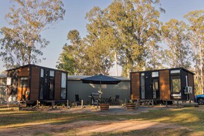 A campsite with two cabins, outdoor seating, and a barbecue area.