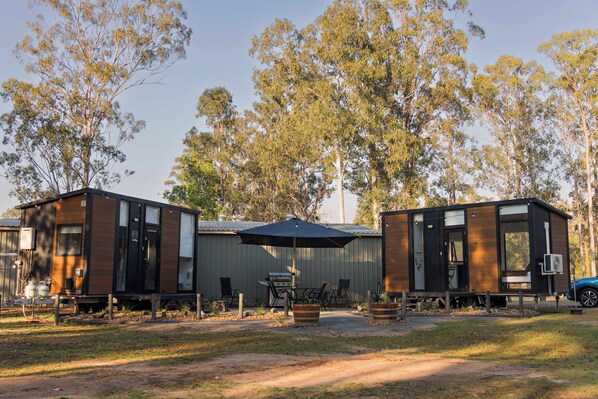 A campsite with two cabins, outdoor seating, and a barbecue area.