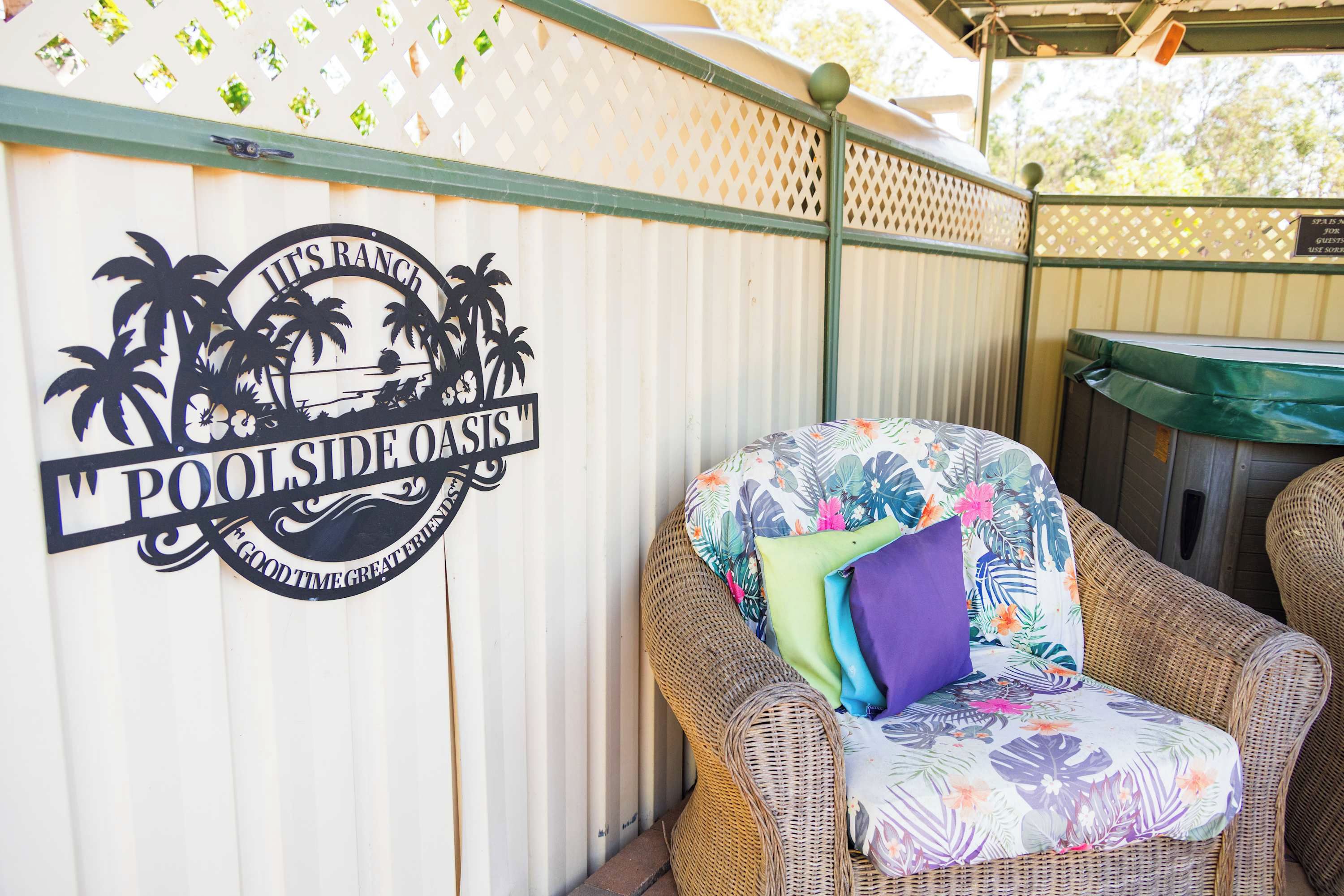 A wicker chair with a floral cushion and a sign with palm trees and text.