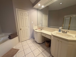 A bathroom with two sinks, a large mirror, a bathtub, and a door. - Gated Valley Ranch Stay, Near DFW Airport & More (Irving)