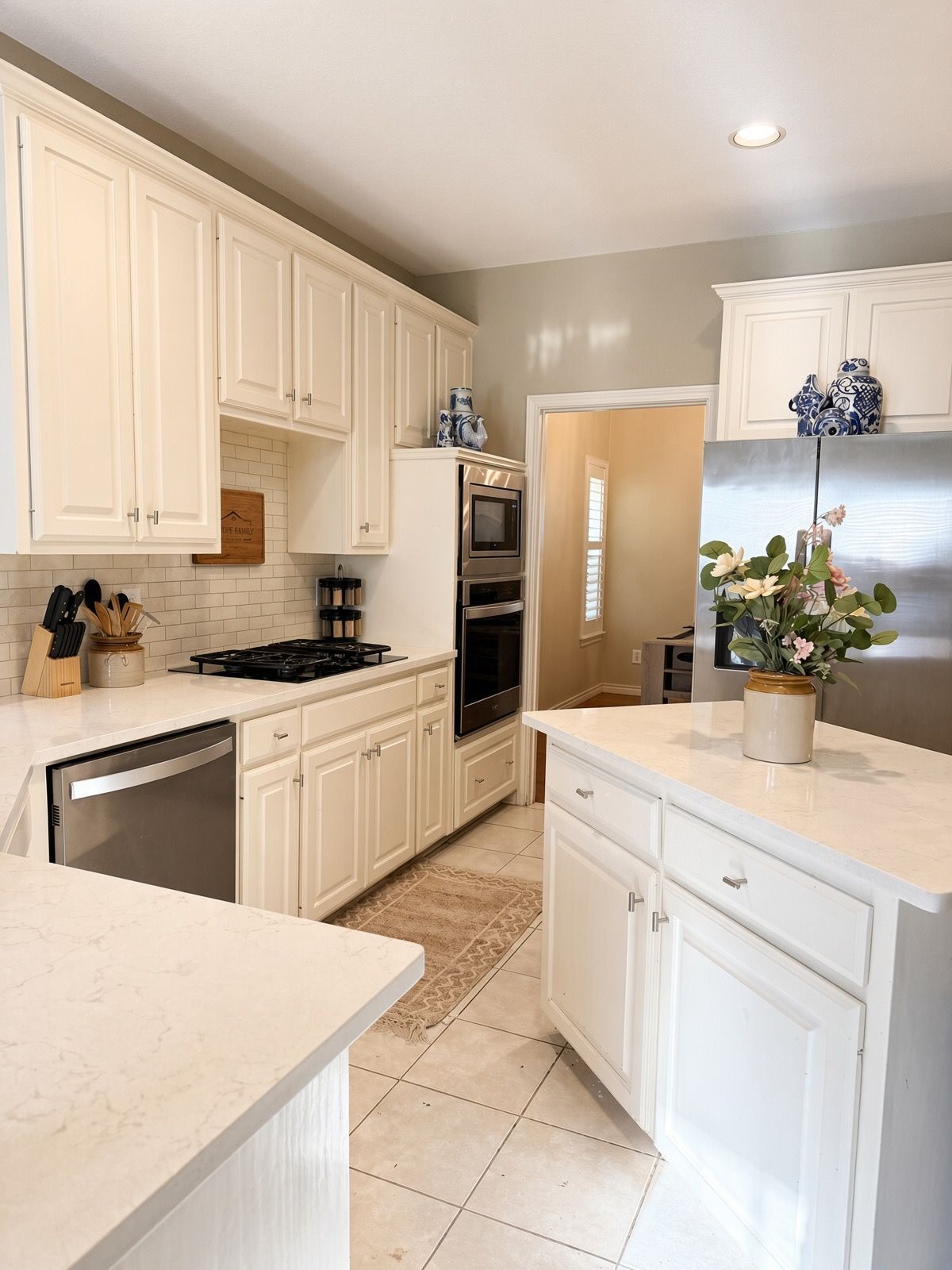A kitchen with white cabinetry, a stainless steel refrigerator, and a built-in oven.