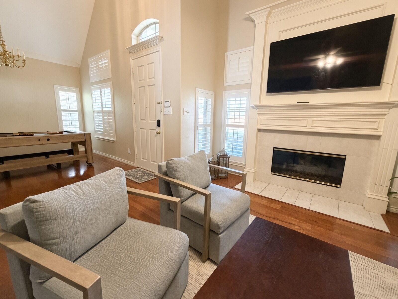 A living room with a fireplace, a television, and a pool table.