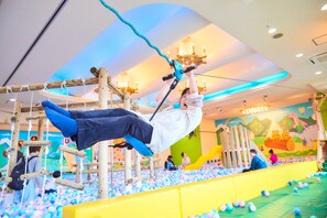 A person hanging from a rope in an indoor play area with a ball pit. - Anda no mori Yamagata Tendou (tendou)
