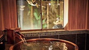 Ein Whirlpool, in den Wasser fließt, ein Fenster mit Blick auf einen Vogel und Vegetation, sowie Holzvertäfelung an den Wänden.