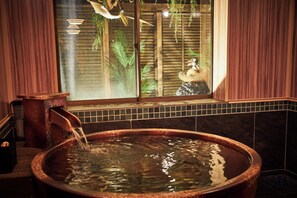 A hot tub with water flowing into it, a window with a view of a bird and foliage, and wooden paneling on the walls. - Anda no mori Yamagata Tendou (tendou)