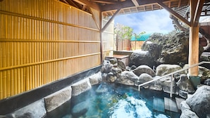 Ein traditionelles japanisches Onsen mit Holzbauten, Steinsbecken und Bambuswand.