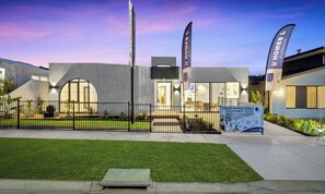 A modern building with a large entrance, a flag, and a signboard. - Spacious 4-Bed Family House Near Gateway Plaza (Leopold)