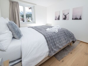 A bedroom with a bed, a window, a grey blanket, and three wall-mounted pictures. - Apartment  by Interhome (Vaz)