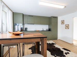 Une cuisine moderne avec des meubles de couleur verte, une table en bois et un tapis en peau de vache.