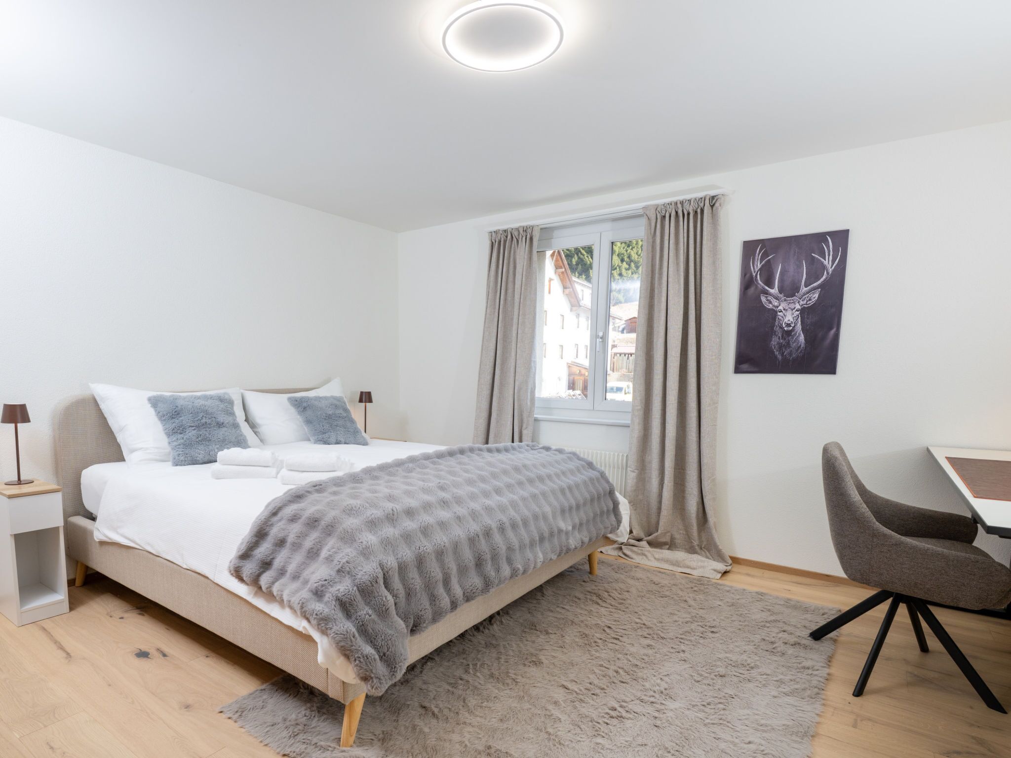 A bedroom with a bed, a desk, and a chair.