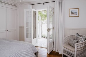 Ein Schlafzimmer mit einem Bett, einem Sessel und einer Tür, die zu einem Außenbereich führt.