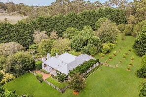 A large house surrounded by a well-maintained lawn and dense trees.
