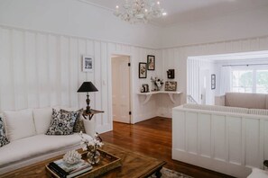 A room with a white sofa, a coffee table with books and a vase, a lamp, and a radiator.