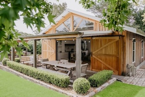 Una casa moderna con patio coperto, zona pranzo e cucina visibile attraverso un'apertura.
