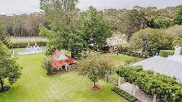 A residential property with a swimming pool, a red-roofed building, and a well-maintained lawn.