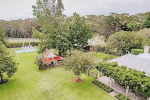 A residential property with a swimming pool, a red-roofed building, and a well-maintained lawn.