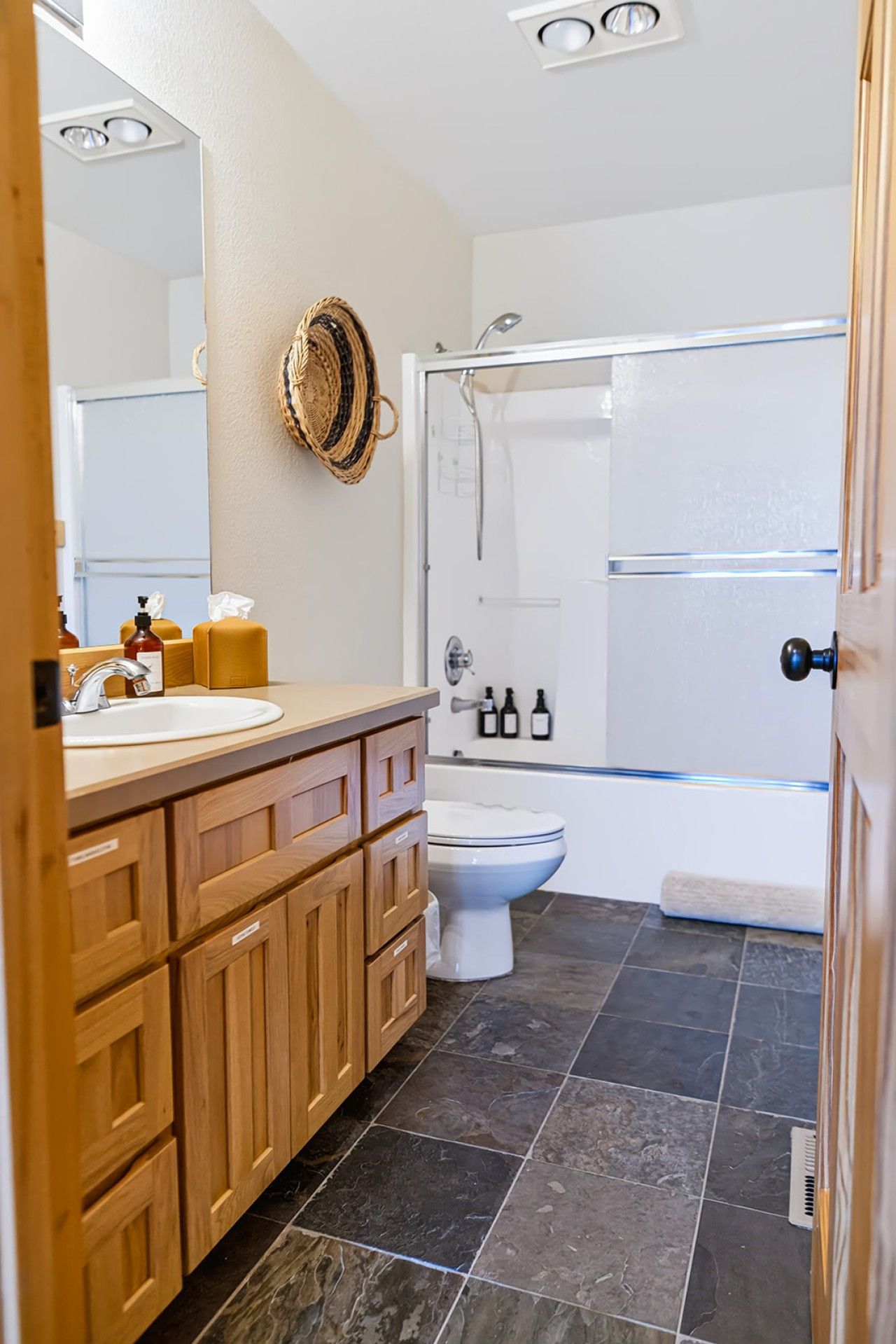 Un baño con tocador de madera, inodoro blanco, cabina de ducha y un espejo grande.
