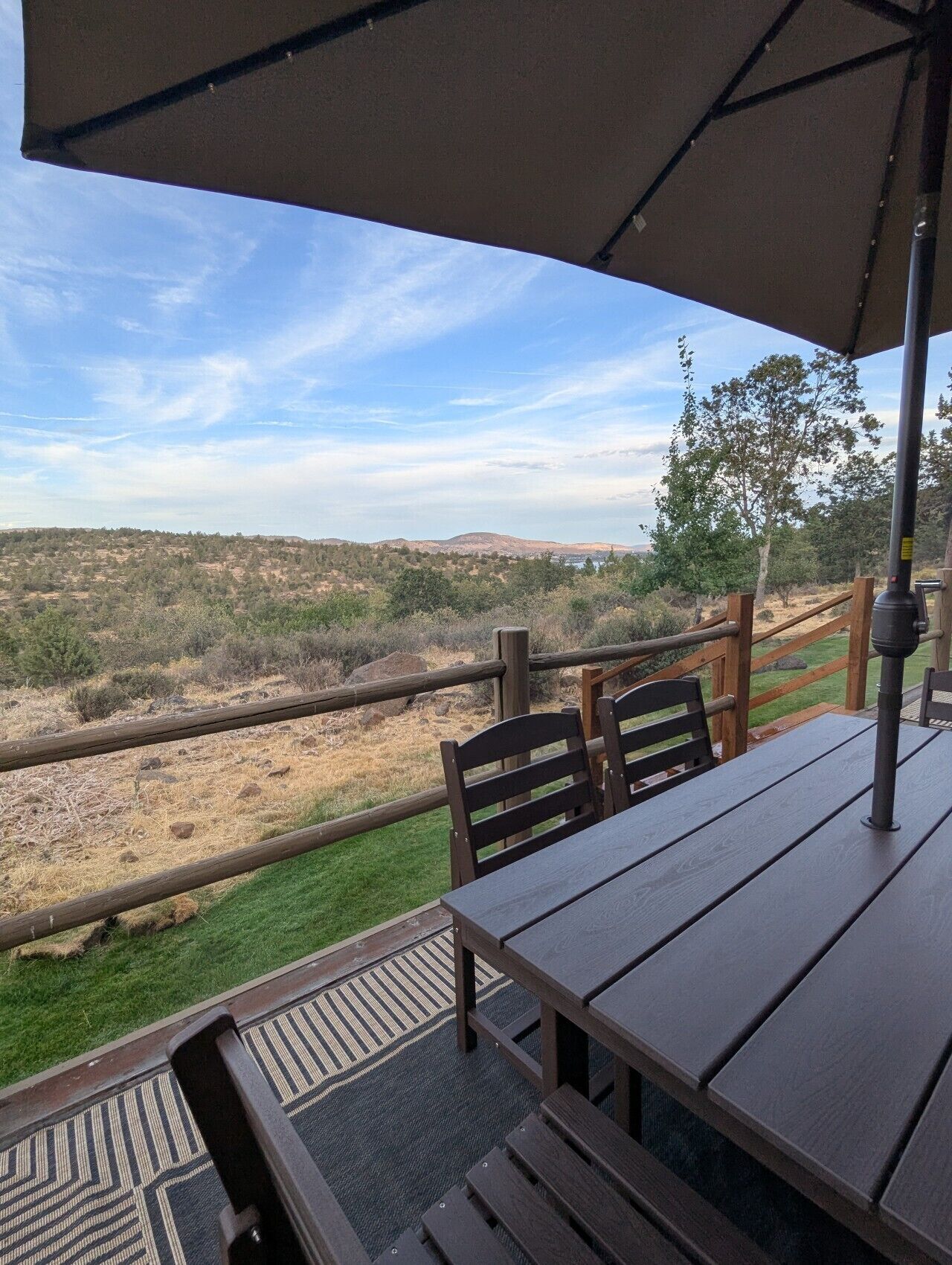 Une terrasse extérieure avec une table et des chaises, donnant sur un paysage vallonné.