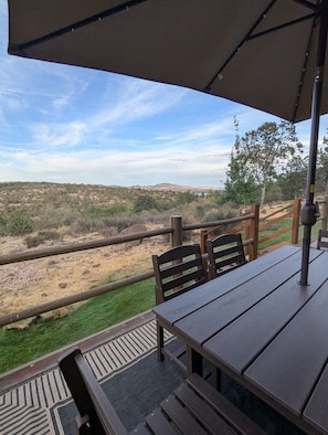 Une terrasse extérieure avec une table et des chaises, donnant sur un paysage vallonné.