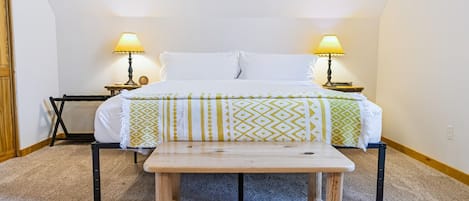 Ein Schlafzimmer mit einem Bett, zwei Nachttischlampen, einer Holzbank und einem kleinen Tisch.