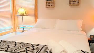 Un dormitorio con cama, lámpara y dos cestas colgantes con flores.