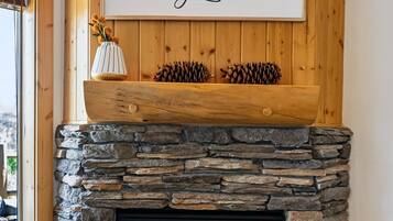 A stone fireplace with a wooden mantel, a framed sign above it, and a window to the left.