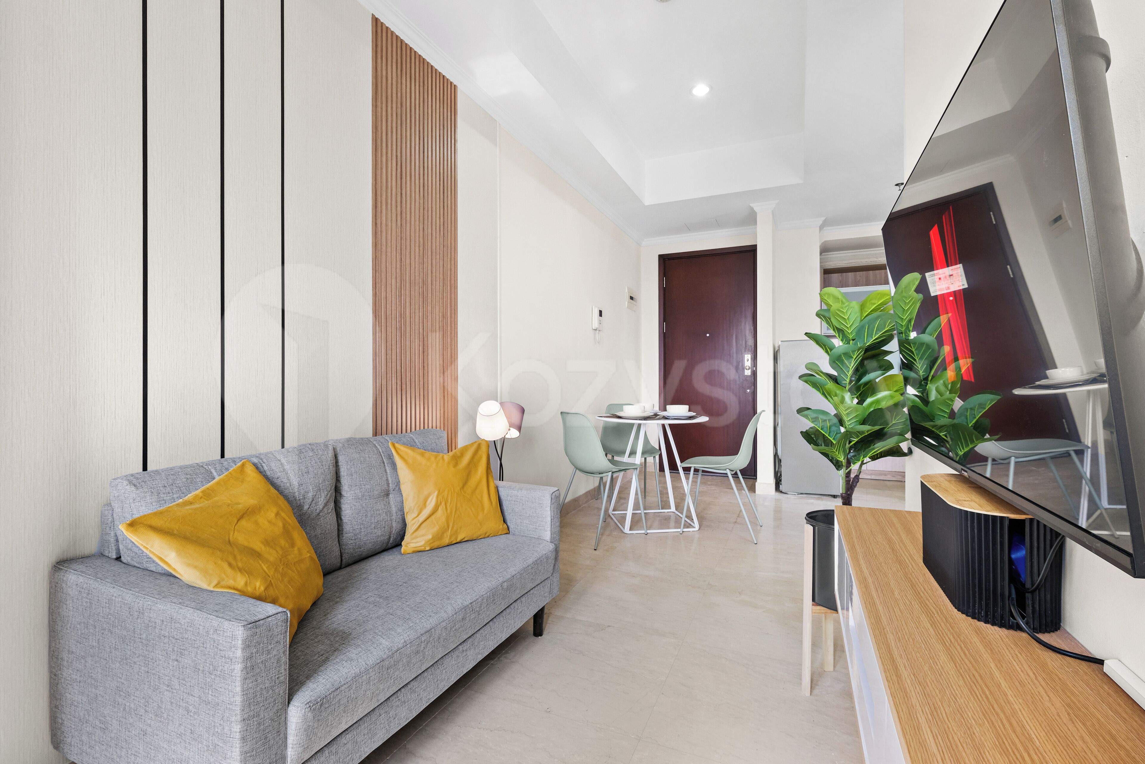 Ein modernes Wohnzimmer mit einem grauen Sofa, einem Couchtisch und einem an der Wand befestigten Flachbildfernseher.