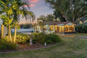 Un immobile residenziale con un giardino curato, una zona patio e una casa con interni visibili.