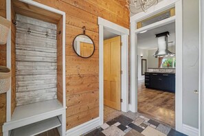 A hallway with a wooden wall, a mirror, a door, and a kitchen area with a stove and cabinets. - The Historic Sugar Mill House with the Guest House (Loveland)