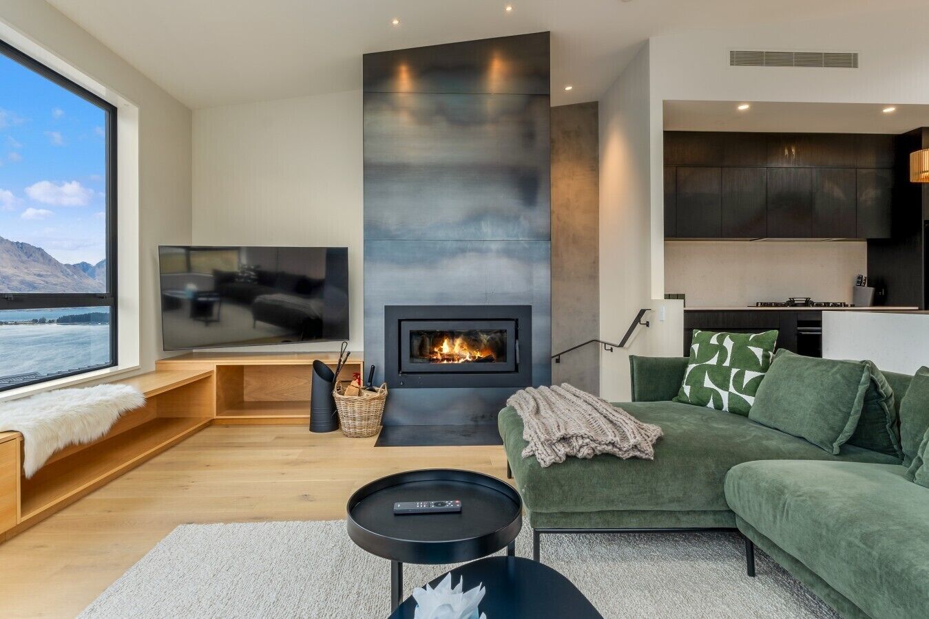 A modern living room with a fireplace, a television, and a view of a body of water.