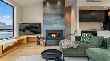 A modern living room with a fireplace, a television, and a view of a body of water.