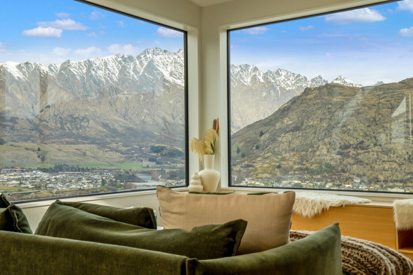 A room with a large window offering a view of snow-capped mountains and a valley below.