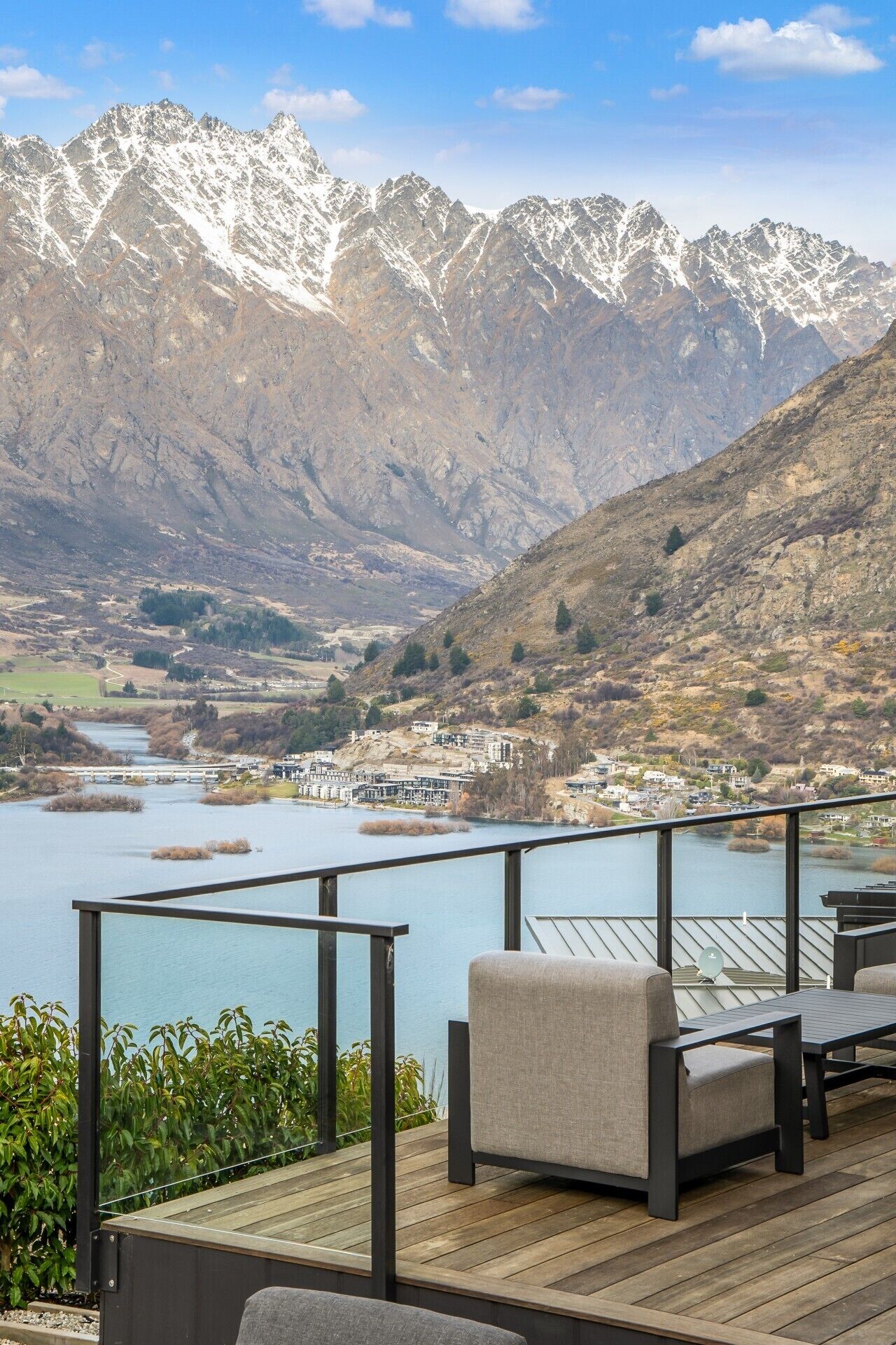 A deck with outdoor furniture overlooking a lake and mountains.