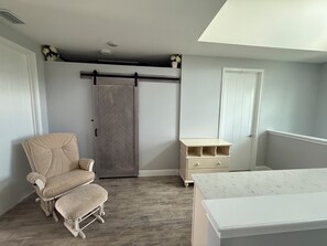 Ein Zimmer mit einem Bett, einem Sessel, einem Kleiderschrank und einem kleinen Tisch.
