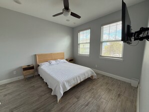A bedroom with a bed, a ceiling fan, two bedside tables, and a TV mounted on the wall. - Paradise Cove Spacious 5BR Home with Private Pool in Kissimmee (Kissimmee)