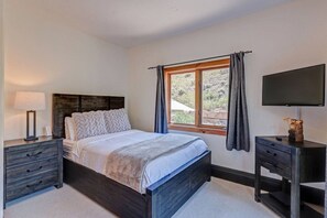 A bedroom with a bed, bedside tables, a TV, and a window with curtains. - Edwards 4BR, Hot Tub,  Mountain Views & Near Vail (Edwards)