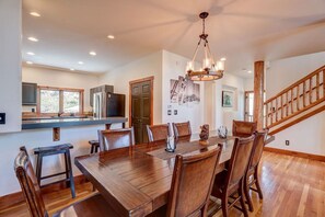 A spacious dining area with a wooden table and chairs, a chandelier, and a kitchen in the background. - Edwards 4BR, Hot Tub,  Mountain Views & Near Vail (Edwards)