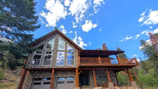 A two-story stone house with a garage, a balcony, and a stone foundation.
