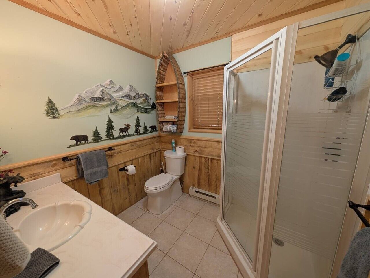 A bathroom with a wooden interior, a toilet, a sink, and a shower area.
