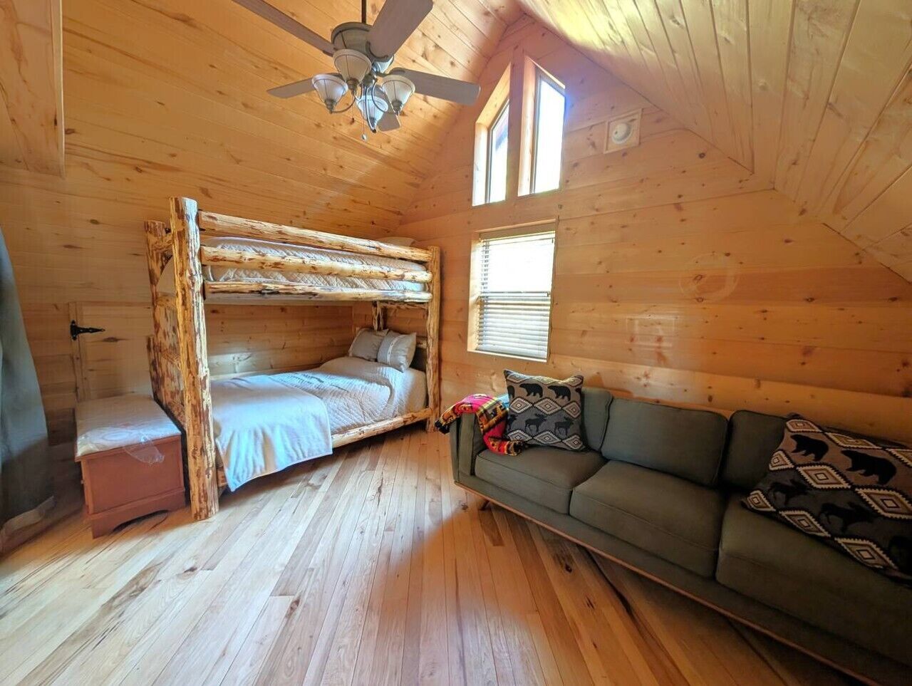 A cabin with a bunk bed, a sofa, and a ceiling fan.