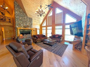 A spacious living room with a fireplace, leather sofas, a coffee table, and a television.