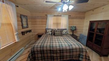 A bedroom with a bed, ceiling fan, window blinds, and a wooden wardrobe.
