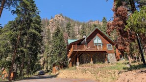 A cabin with a stone foundation, wooden exterior, and a balcony.
