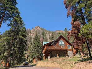 A cabin with a stone foundation, wooden exterior, and a balcony. - Almont Mountain Cabin | Hot Tub & Forest Views (Almont)