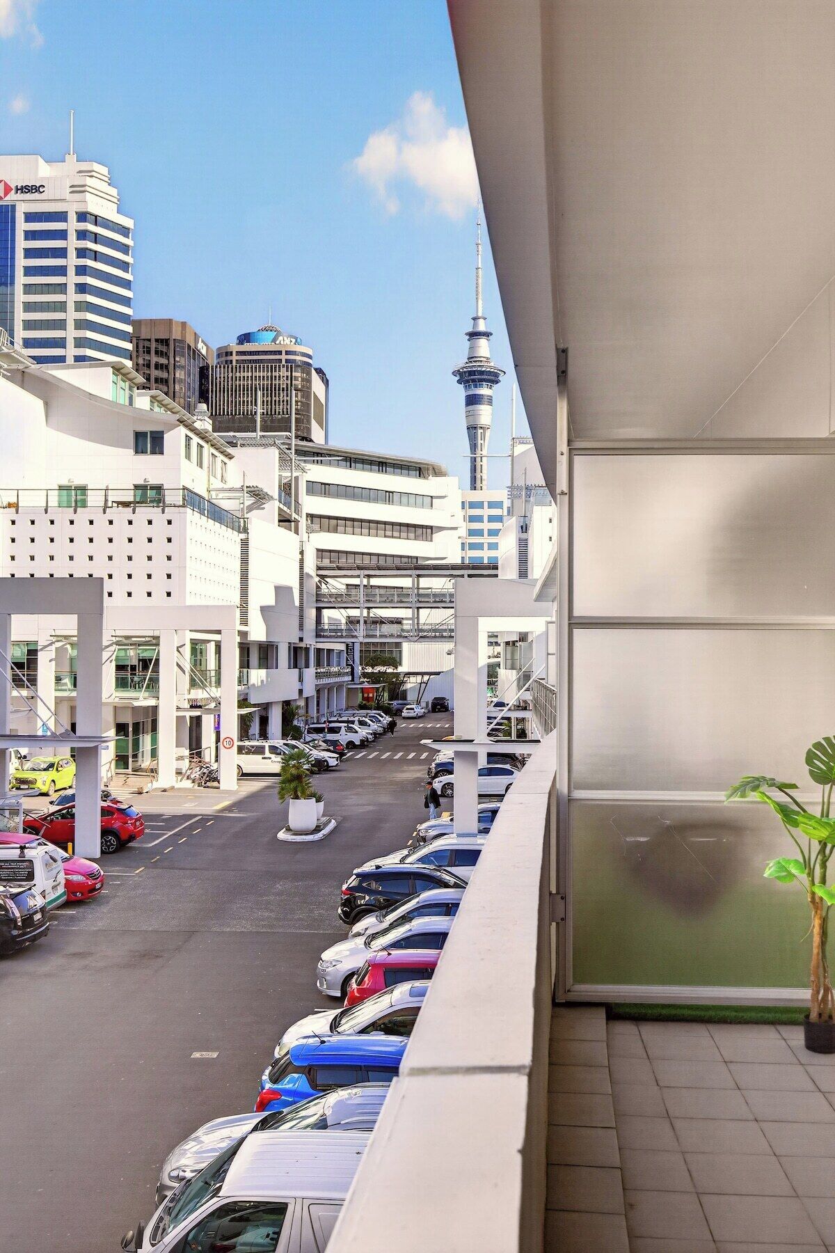 Vista de una calle con un edificio moderno, una torre y coches estacionados.