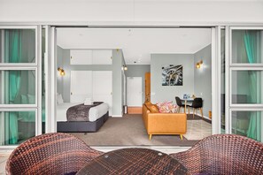 Ein Hotelzimmer mit Bett, einer Couch, einem Esstisch und Blick durch eine Glastür.