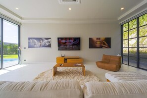 Uma sala de estar moderna com uma janela grande, uma TV de tela plana e obras de arte nas paredes.